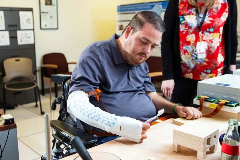 在2010年遭受严重脊髓损伤后，伊恩·伯克哈特在他的运动皮层植入了微型芯片，将大脑电信号转到电脑上控制手臂，使其能够再次抓住和感觉物体。图源/Battelle Memorial Institute